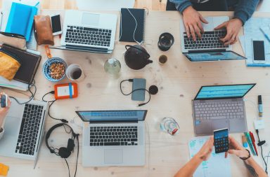 people sitting down near table with assorted laptop computers